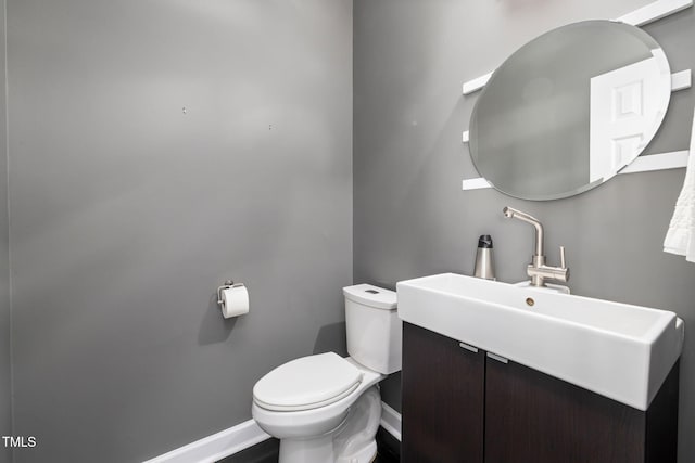 half bath with a sink, toilet, and baseboards