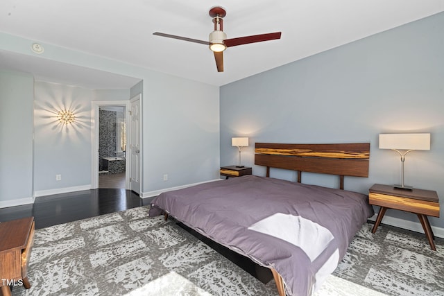 bedroom with ensuite bathroom, ceiling fan, dark wood-type flooring, and baseboards