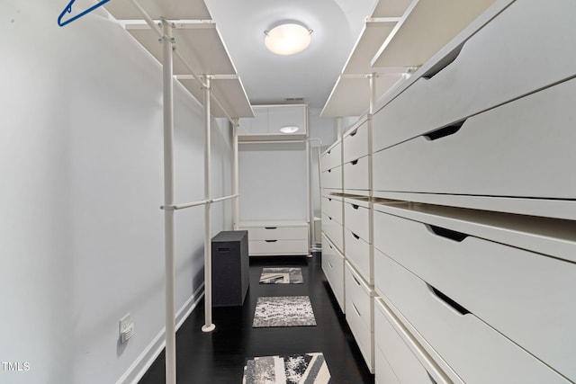 walk in closet with dark wood-type flooring