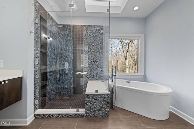 bathroom featuring a stall shower, baseboards, a freestanding bath, vanity, and recessed lighting