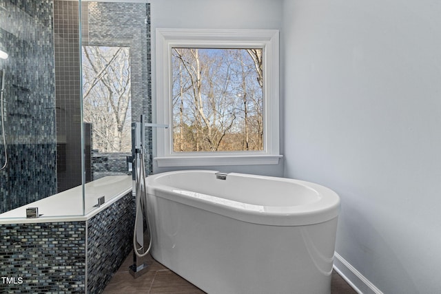 full bath featuring a soaking tub, baseboards, and tile patterned floors