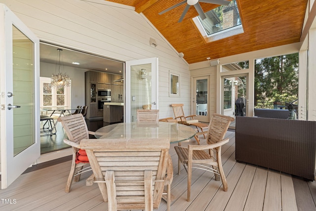 sunroom / solarium featuring lofted ceiling with skylight, wood ceiling, and ceiling fan with notable chandelier