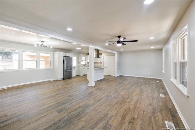 unfurnished living room featuring recessed lighting, baseboards, visible vents, dark wood finished floors, and ceiling fan with notable chandelier