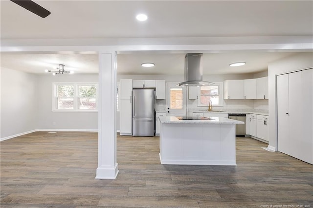 kitchen featuring island range hood, a sink, white cabinets, open floor plan, and appliances with stainless steel finishes