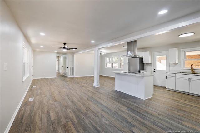 kitchen with open floor plan, freestanding refrigerator, island exhaust hood, and white cabinetry