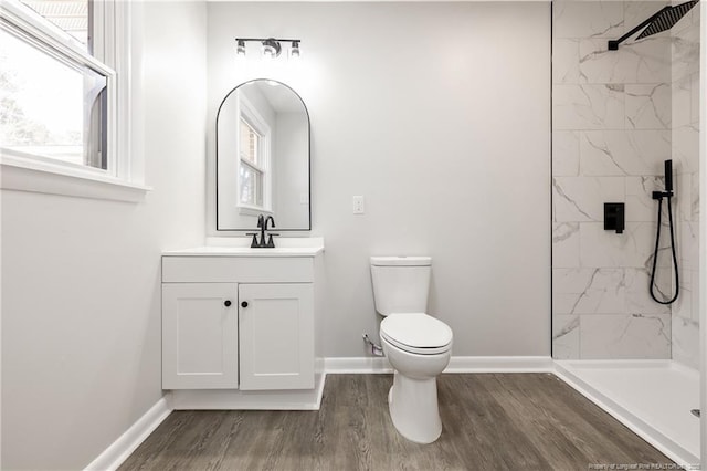 full bath featuring baseboards, vanity, a marble finish shower, and wood finished floors