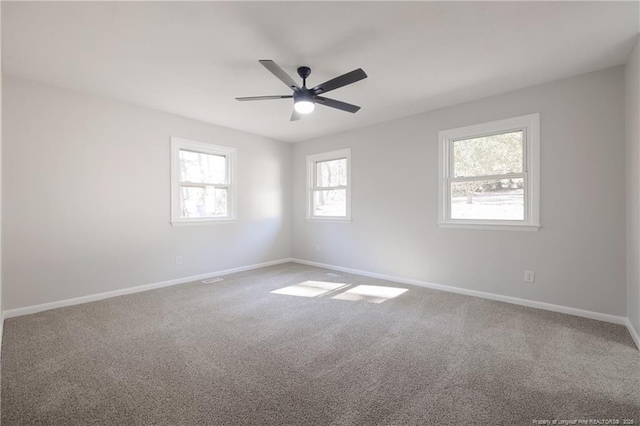 carpeted empty room with ceiling fan and baseboards