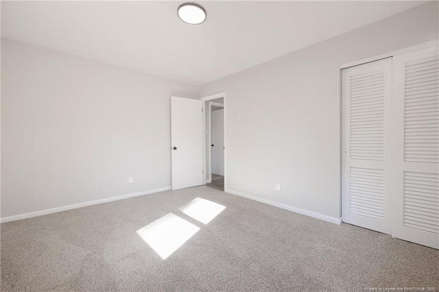 unfurnished bedroom with carpet floors, baseboards, and a closet