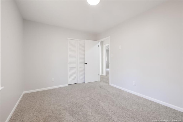 unfurnished bedroom featuring carpet, baseboards, and a closet