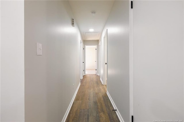 corridor featuring attic access, dark wood-style flooring, and baseboards