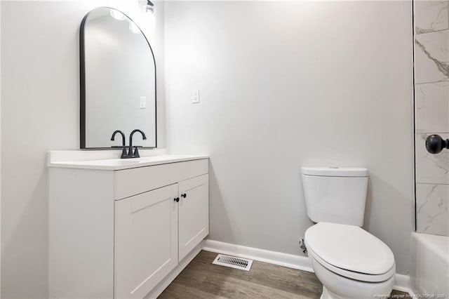 bathroom featuring toilet, wood finished floors, vanity, visible vents, and baseboards