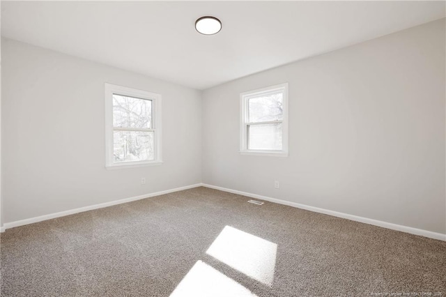 carpeted spare room featuring baseboards