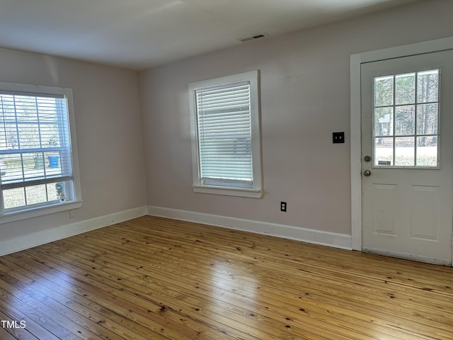 foyer entrance with baseboards, visible vents, and light wood finished floors