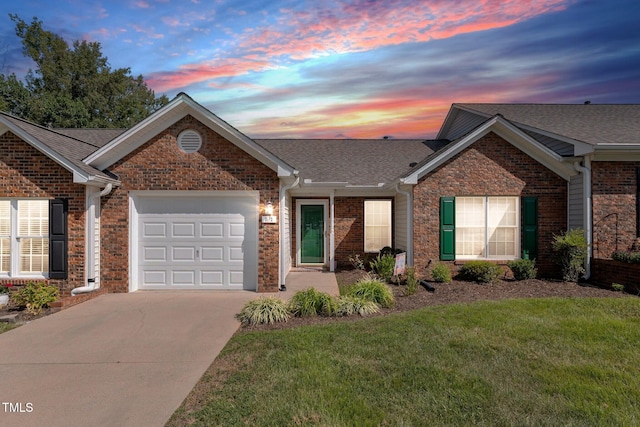 ranch-style house featuring an attached garage, a yard, concrete driveway, and brick siding