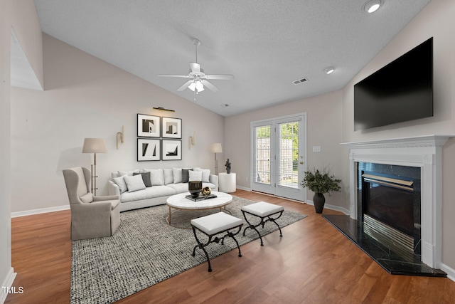 living area with lofted ceiling, a fireplace, baseboards, and wood finished floors