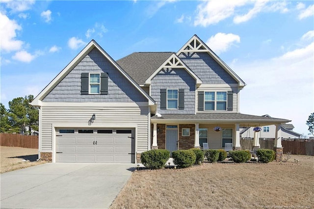 craftsman inspired home with a porch, concrete driveway, a front yard, fence, and a garage