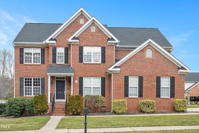 view of front of property with a front lawn, brick siding, and a shingled roof