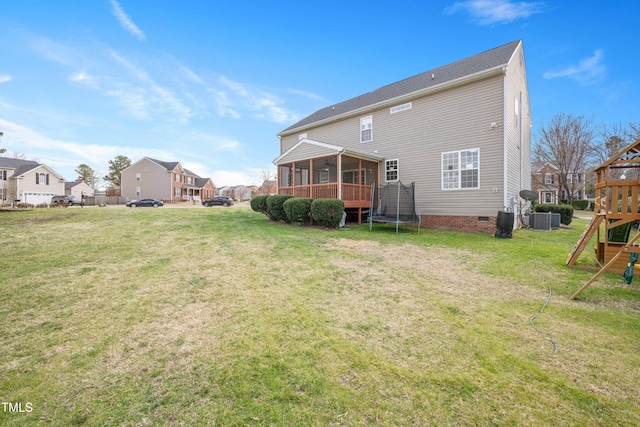 back of property featuring crawl space, a lawn, a trampoline, and a sunroom