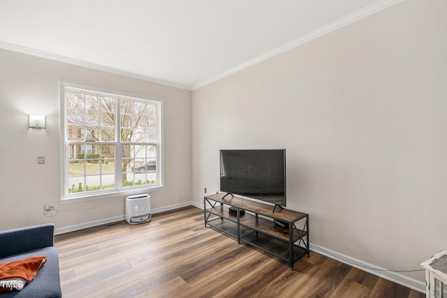 living area featuring ornamental molding, baseboards, and wood finished floors