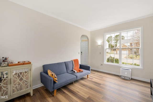 sitting room featuring arched walkways, crown molding, baseboards, and wood finished floors