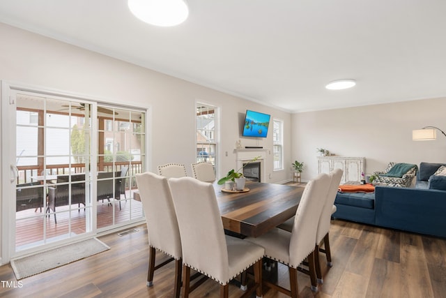 dining room with a glass covered fireplace, visible vents, dark wood finished floors, and ornamental molding