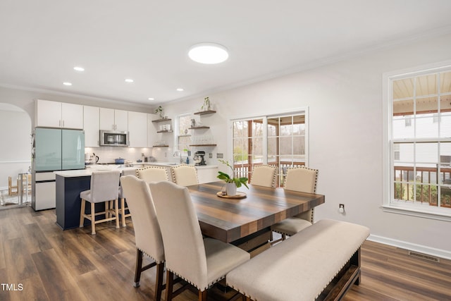 dining area with dark wood finished floors, baseboards, visible vents, and ornamental molding