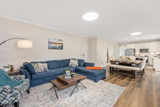 living room featuring baseboards, ornamental molding, recessed lighting, wood finished floors, and arched walkways