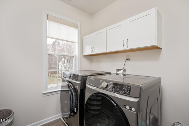 washroom featuring washing machine and dryer, cabinet space, baseboards, and a wealth of natural light