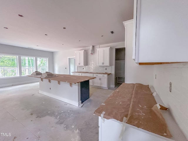 1905 Old Bramble Ln Unit 4, Fuquay Varina, NC 27526 - kitchen with white cabinets, decorative backsplash, a kitchen island, a kitchen breakfast bar, and concrete floors