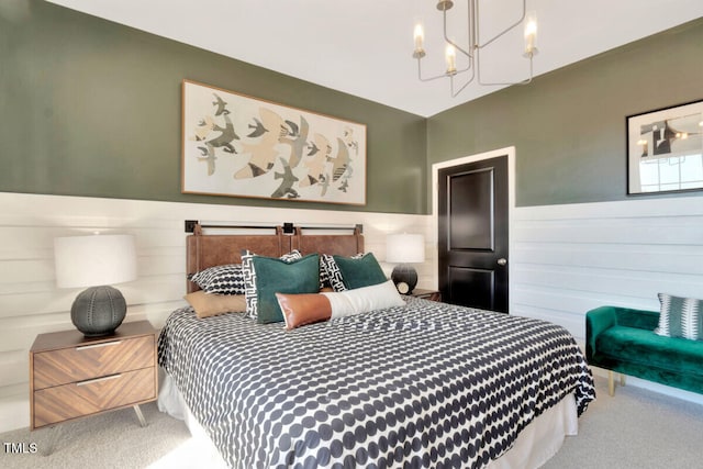 carpeted bedroom featuring a wainscoted wall and a chandelier