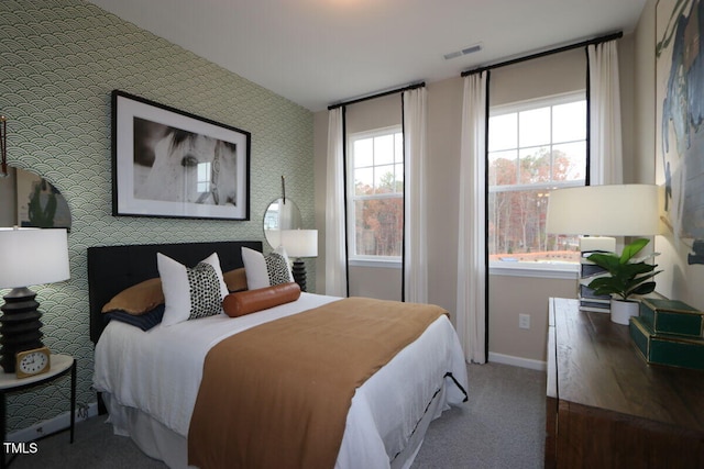 bedroom featuring an accent wall, dark carpet, visible vents, and baseboards