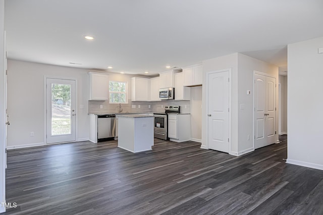 kitchen with white cabinets, light countertops, appliances with stainless steel finishes, a center island, and tasteful backsplash