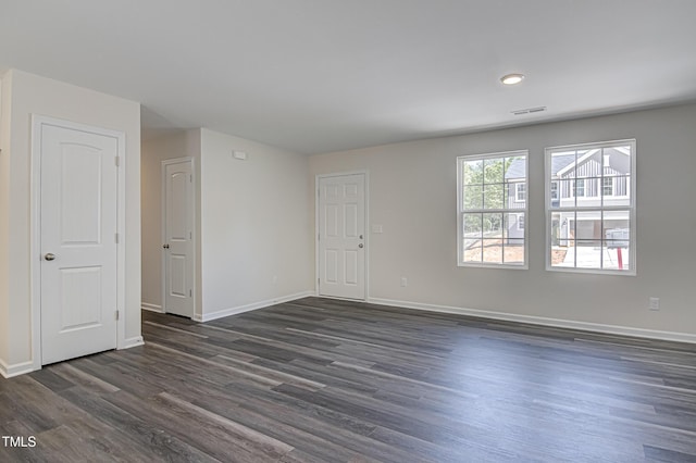 spare room with visible vents, baseboards, and dark wood-type flooring