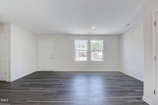 unfurnished room featuring dark wood-style floors, visible vents, and baseboards