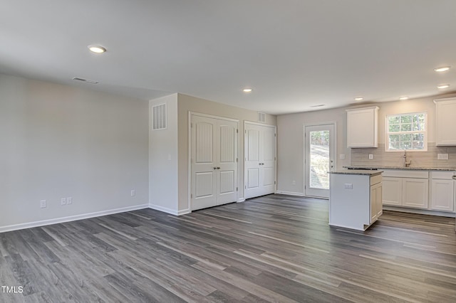 kitchen with dark wood finished floors, visible vents, decorative backsplash, white cabinetry, and baseboards