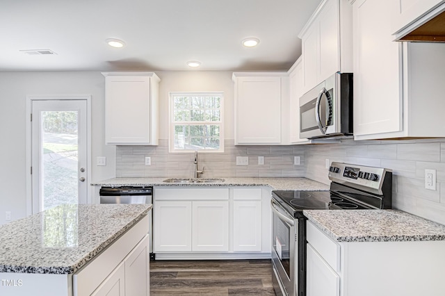 kitchen featuring a sink, visible vents, white cabinetry, appliances with stainless steel finishes, and light stone countertops