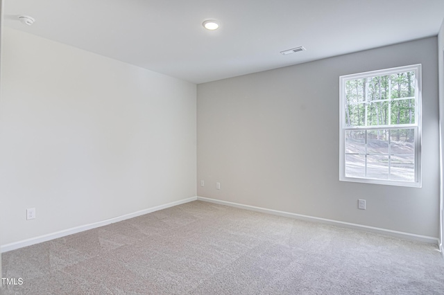 empty room with carpet floors, recessed lighting, visible vents, and baseboards