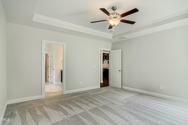 unfurnished bedroom featuring baseboards, a raised ceiling, visible vents, and light colored carpet