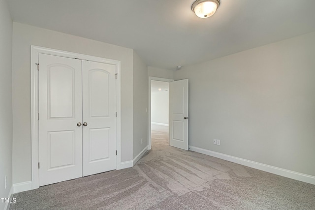 unfurnished bedroom with baseboards, a closet, and light colored carpet