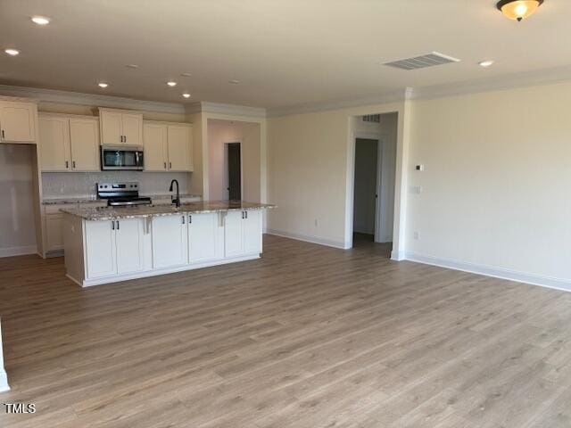 190 Sage Ln Unit 015, Four Oaks, NC 27524 - kitchen with appliances with stainless steel finishes, crown molding, baseboards, light wood finished floors, and white cabinetry