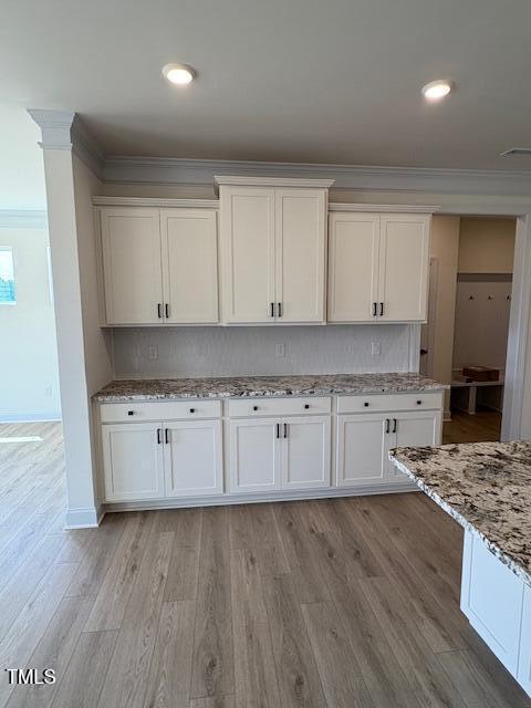 190 Sage Ln Unit 015, Four Oaks, NC 27524 - kitchen featuring crown molding, light wood-type flooring, white cabinets, light stone counters, and baseboards