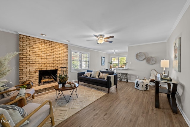 living area featuring a brick fireplace, crown molding, baseboards, and wood finished floors