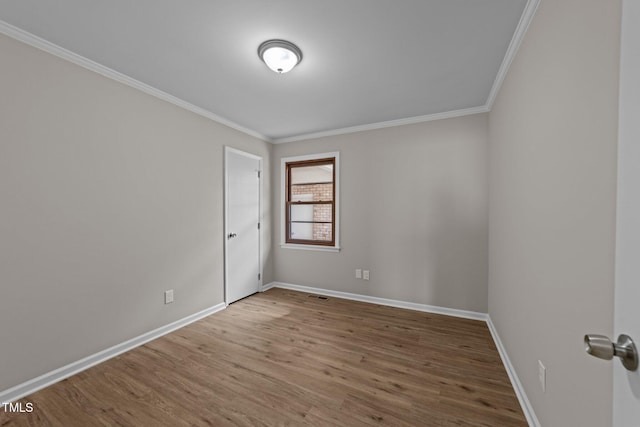 spare room with ornamental molding, baseboards, and wood finished floors