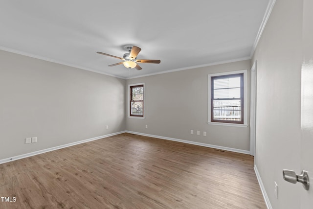 empty room featuring wood finished floors, visible vents, a ceiling fan, baseboards, and ornamental molding