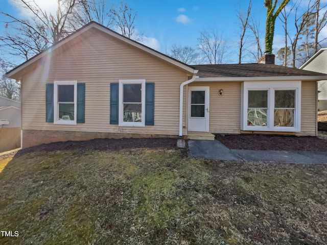 view of front of house featuring a chimney and a front lawn