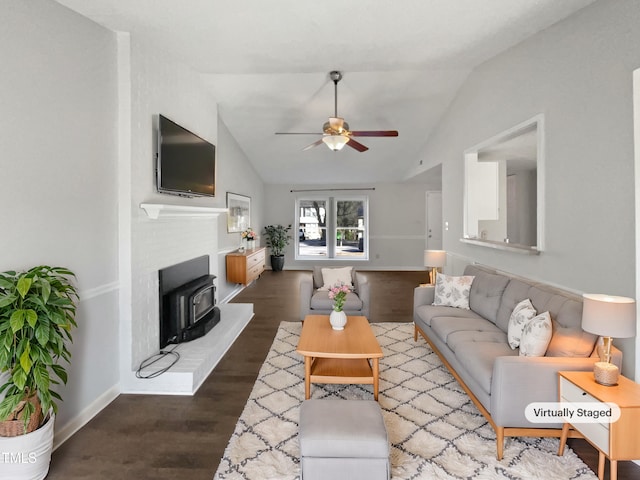 living room with dark wood-type flooring, a ceiling fan, a wood stove, vaulted ceiling, and baseboards