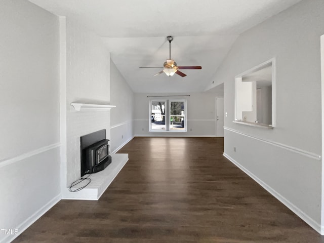 unfurnished living room with ceiling fan, baseboards, vaulted ceiling, dark wood finished floors, and a wood stove