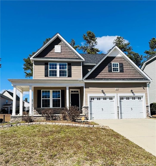 craftsman-style home with an attached garage, a porch, concrete driveway, and a front yard