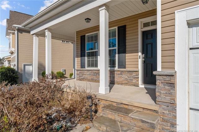 view of exterior entry featuring stone siding and a porch