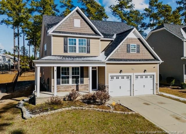 craftsman-style house featuring covered porch, concrete driveway, stone siding, and an attached garage